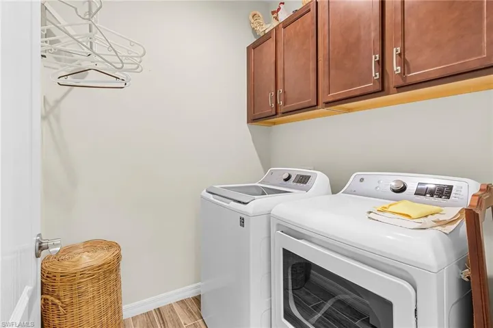 Washroom featuring cabinet space, washer and clothes dryer, and light wood-style floors
