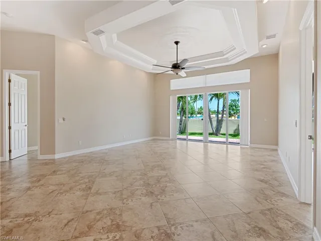 Tiled spare room with ceiling fan and a tray ceiling