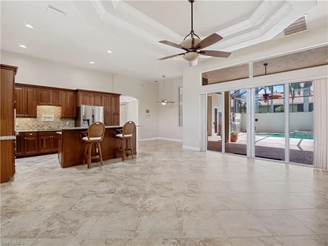 Kitchen with a breakfast bar, a center island, a tray ceiling, ceiling fan, and stainless steel refrigerator with ice dispenser