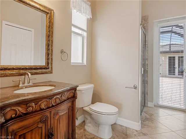 Bathroom with a shower with shower door, vanity, tile patterned flooring, and toilet