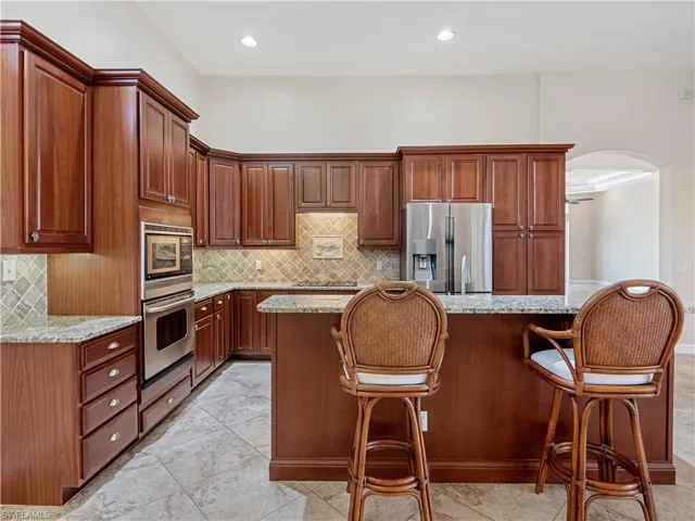 Kitchen featuring light tile patterned floors, stainless steel fridge with ice dispenser, built in microwave, and a kitchen island