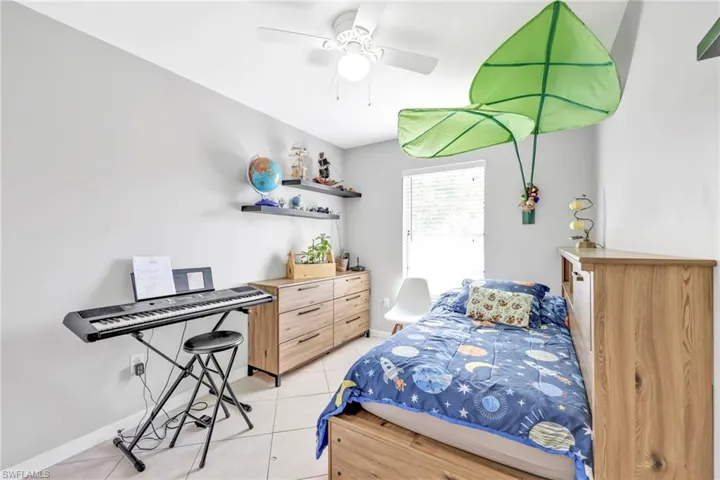 Bedroom with light tile patterned floors, baseboards, and a ceiling fan
