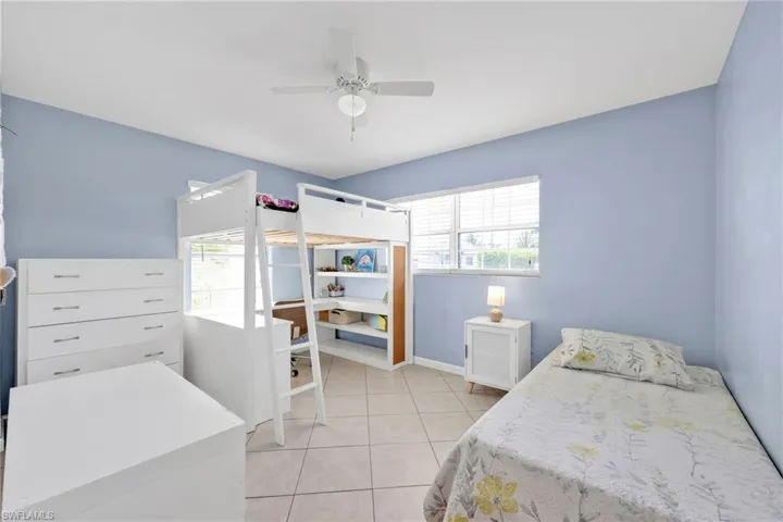 Bedroom with multiple windows, light tile patterned floors, baseboards, and an office area