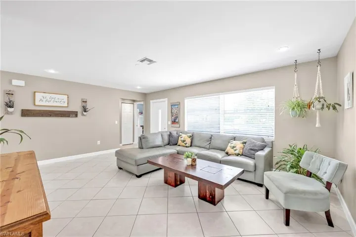 Living room featuring baseboards, light tile patterned floors, and recessed lighting