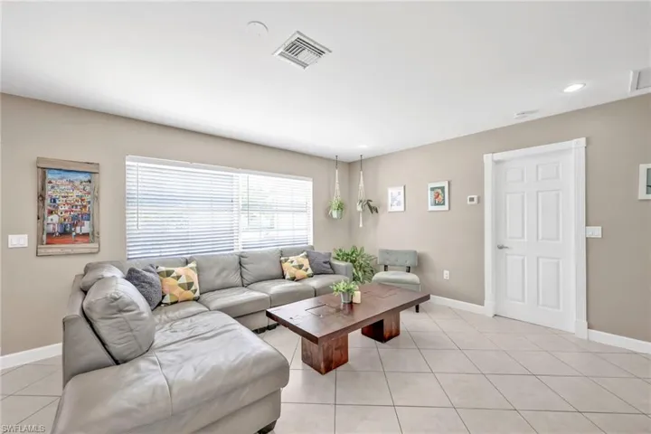 Living room with light tile patterned flooring, baseboards, and recessed lighting