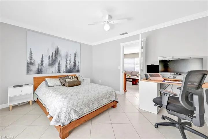 Bedroom with ornamental molding, an office area, light tile patterned floors, and baseboards