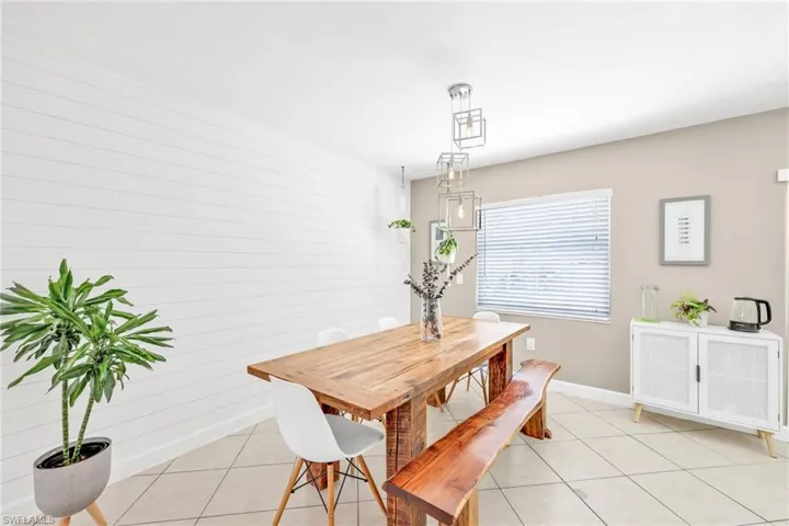 Dining space with light tile patterned floors, shiplap wall and baseboards