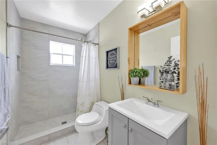 Bathroom with a tile shower, toilet, vanity, and tile patterned floors