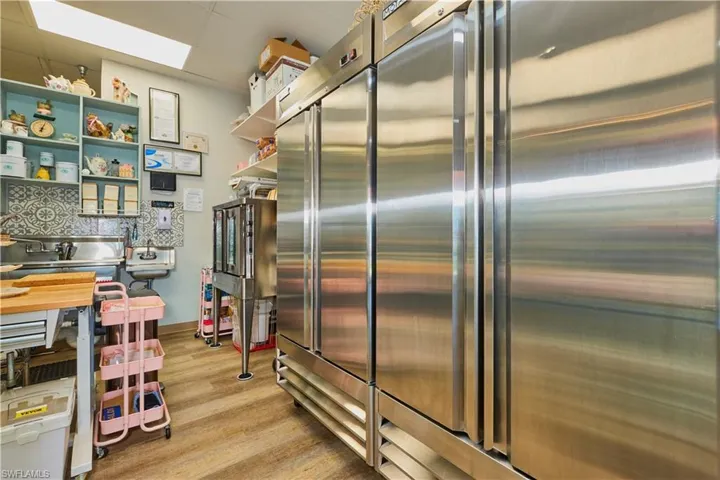 Kitchen with stainless steel built in fridge, light wood finished floors, and open shelves