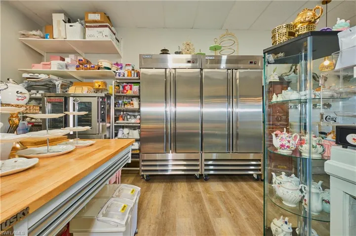Kitchen featuring a drop ceiling, wood finished floors, beverage cooler, built in refrigerator, and wooden counters