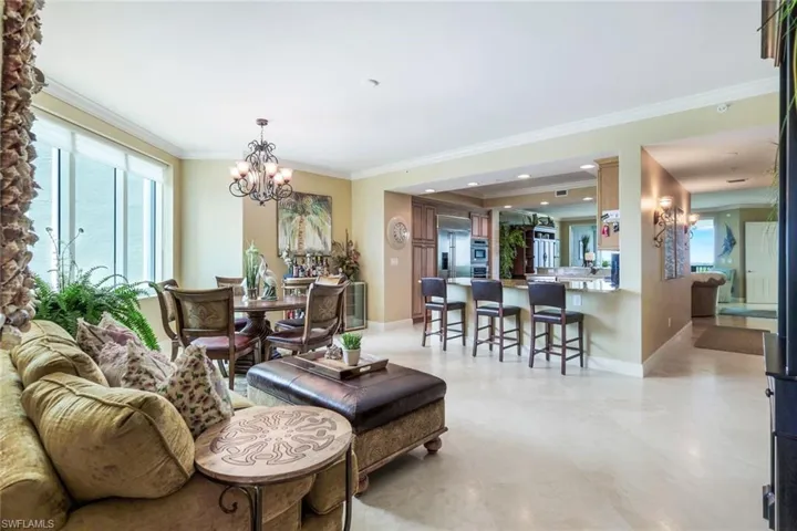 Living room with an inviting chandelier, crown molding, light tile flooring, and ornate columns