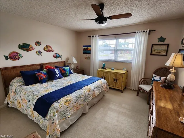 Carpeted bedroom featuring a textured ceiling and ceiling fan