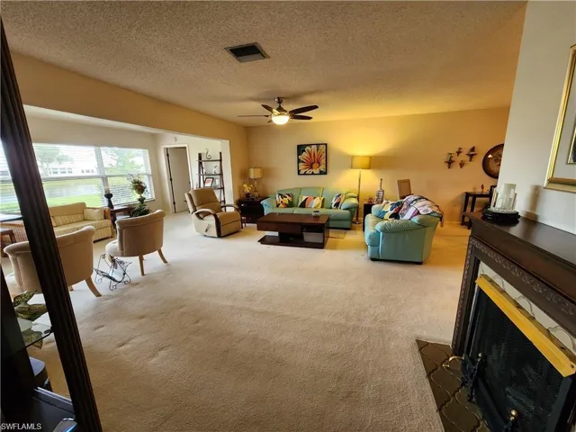 Living room featuring a textured ceiling, carpet floors, and ceiling fan