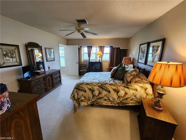 Bedroom with light carpet, a textured ceiling, and ceiling fan