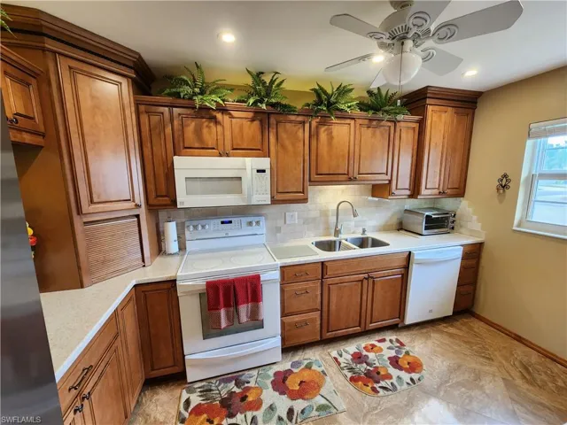 Kitchen featuring ceiling fan, tasteful backsplash, white appliances, light tile floors, and sink