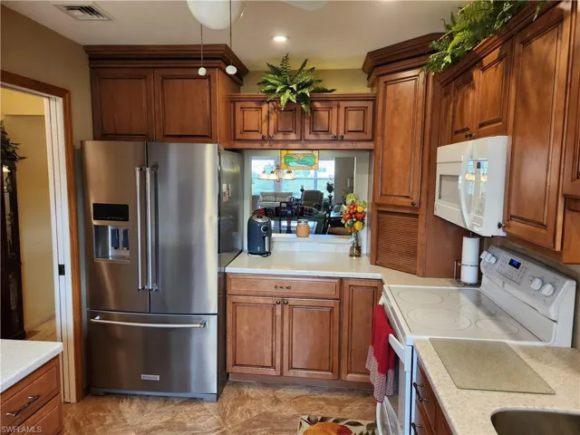 Kitchen with ceiling fan, light tile flooring, and white appliances