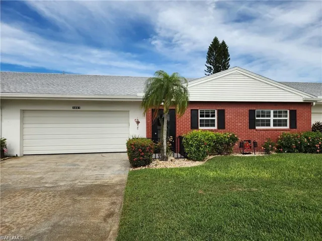 Single story home with a garage and a front lawn