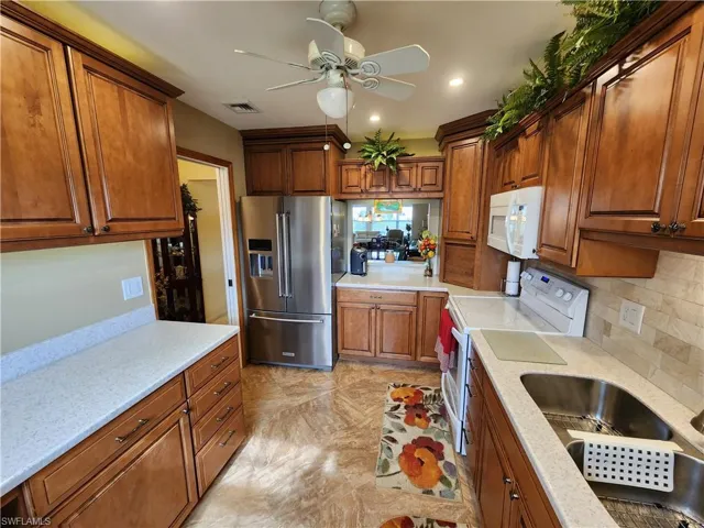 Kitchen with ceiling fan, tasteful backsplash, sink, white appliances, and light tile floors