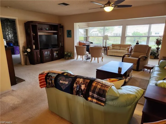 Living room featuring a textured ceiling, ceiling fan, and carpet floors