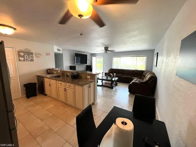 Kitchen featuring a peninsula with stone-finish countertops, light-toned cabinetry, ceramic tile flooring, and dual ceiling fans
