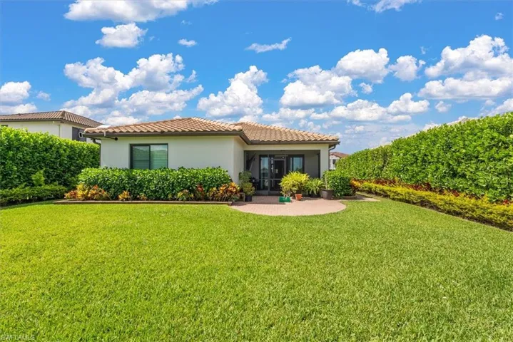 Expansive green lawn with mature privacy planter hedges and a rear screened patio
