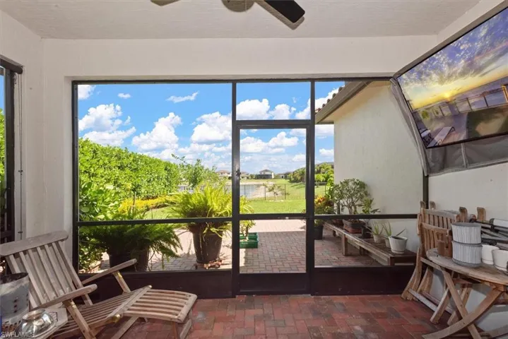 Screened patio with brick flooring, overlooking a green landscape with a distant body of water