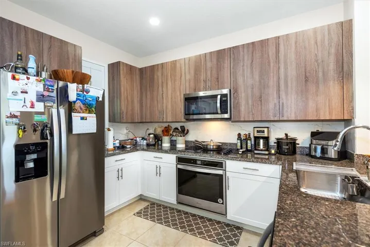Kitchen featuring wood-finish upper cabinetry, white lower cabinetry, and granite countertops