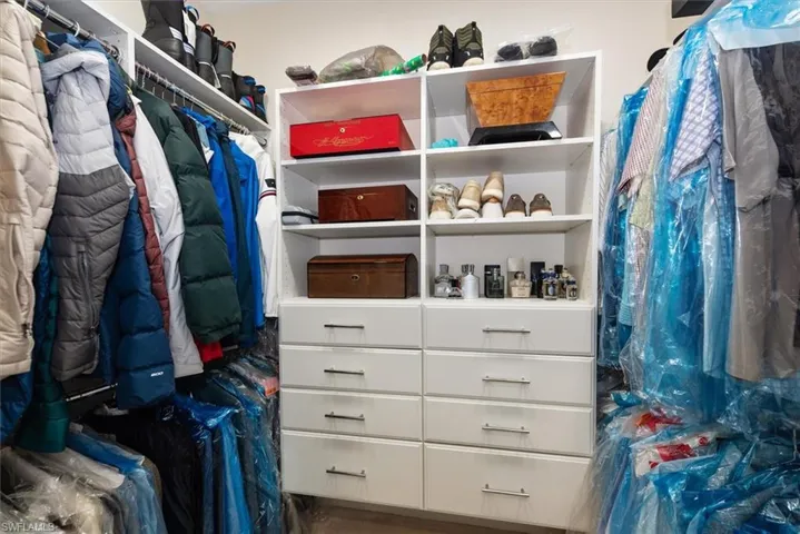 Custom closet system in mast bedroom featuring white shelving units, built-in drawers with modern pulls, and integrated hanging rods for garment storage