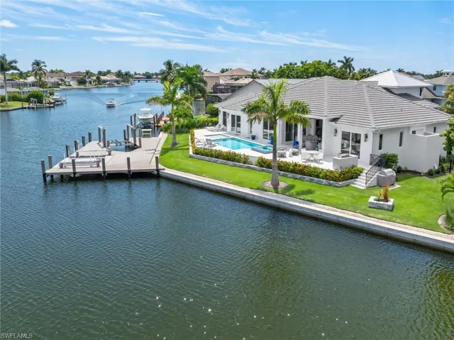 Back of house featuring a patio, a water view, and a lawn