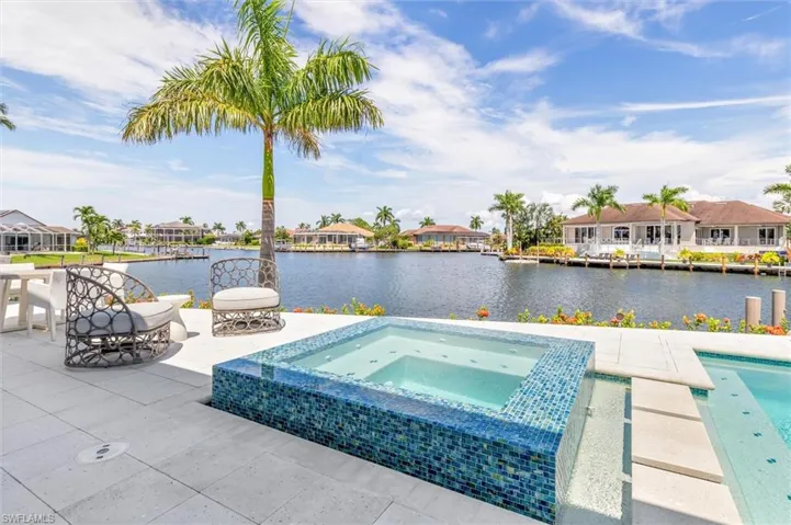 View of swimming pool featuring a patio, a water view, and an in ground hot tub
