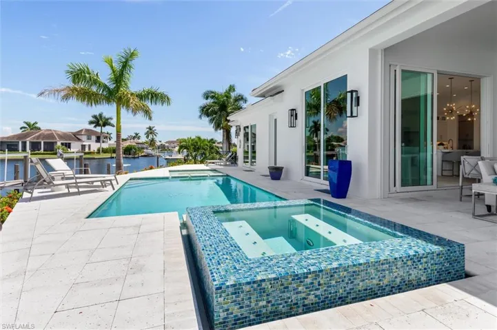 View of pool featuring a water view, an in ground hot tub, and a patio area