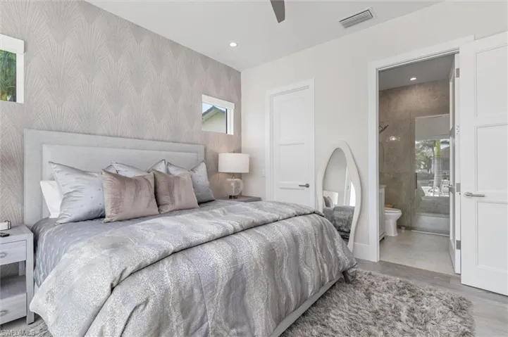 Bedroom featuring ceiling fan, light wood-type flooring, and ensuite bathroom