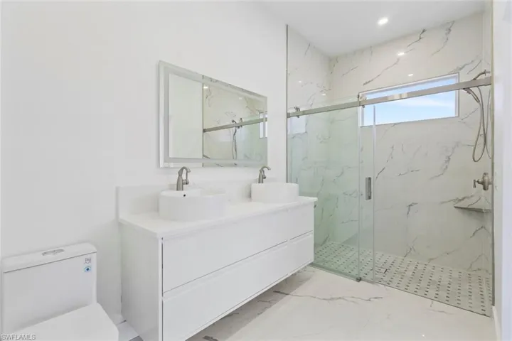 Master Bathroom featuring double vanity, a marble finish shower, and light marble finish flooring