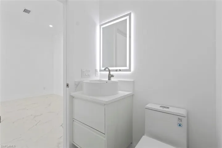 Half bath featuring light marble finish floors, vanity, and recessed lighting