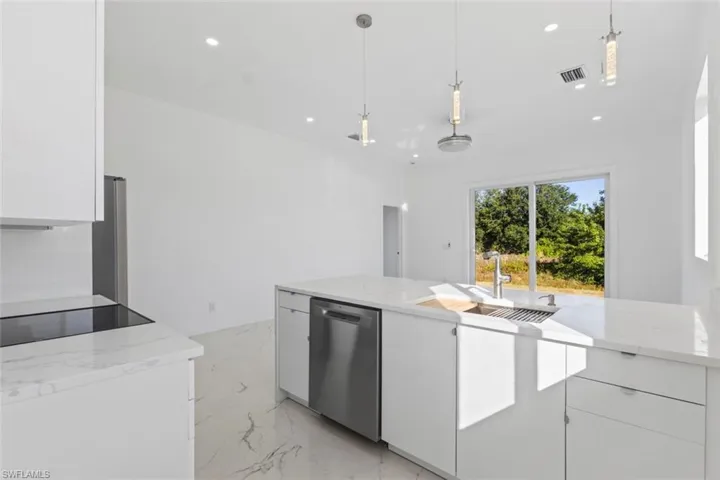 Kitchen with white cabinetry, light marble finish flooring, hanging light fixtures, light stone countertops, and recessed lighting