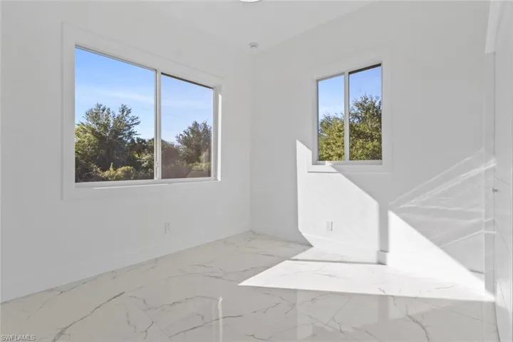 3rd bedroom with baseboards and light marble finish floors