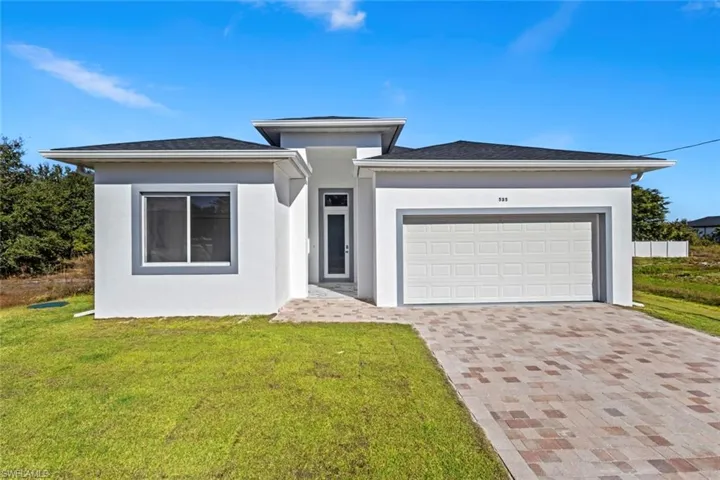 Prairie-style home with stucco siding, decorative driveway, a front yard, and a garage