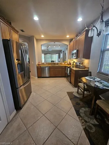 Kitchen with appliances with stainless steel finishes, arched walkways, light tile patterned flooring, recessed lighting, and a textured ceiling