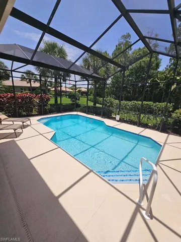Swimming pool featuring a sunroom, glass enclosure, and a patio