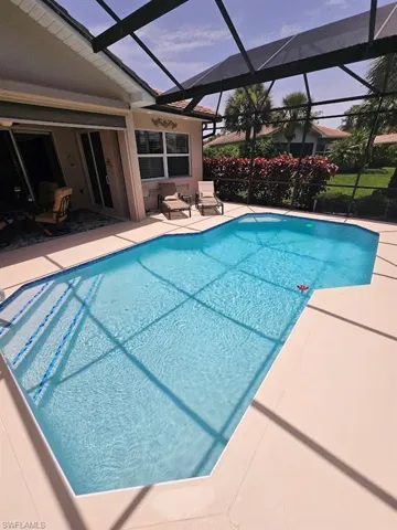 Outdoor pool with a sunroom, a patio area, and glass enclosure