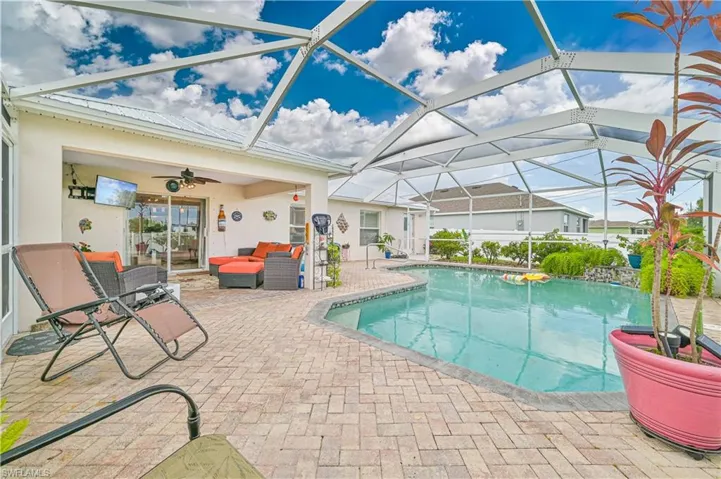 View of swimming pool featuring ceiling fan, outdoor lounge area, glass enclosure, and a patio area