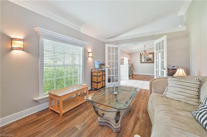 Living room featuring vaulted ceiling, french doors, hardwood / wood-style floors, and ornamental molding