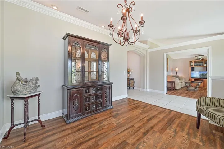 Dining room with crown molding, tile patterned floors, and an inviting chandelier