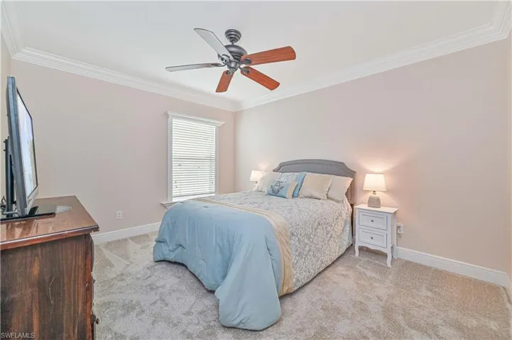 Carpeted bedroom featuring ceiling fan and crown molding