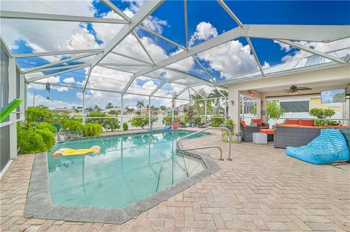 View of swimming pool featuring glass enclosure, ceiling fan, a patio area, and an outdoor hangout area