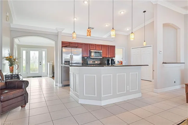 Kitchen with appliances with stainless steel finishes, ornamental molding, backsplash, and hanging light fixtures