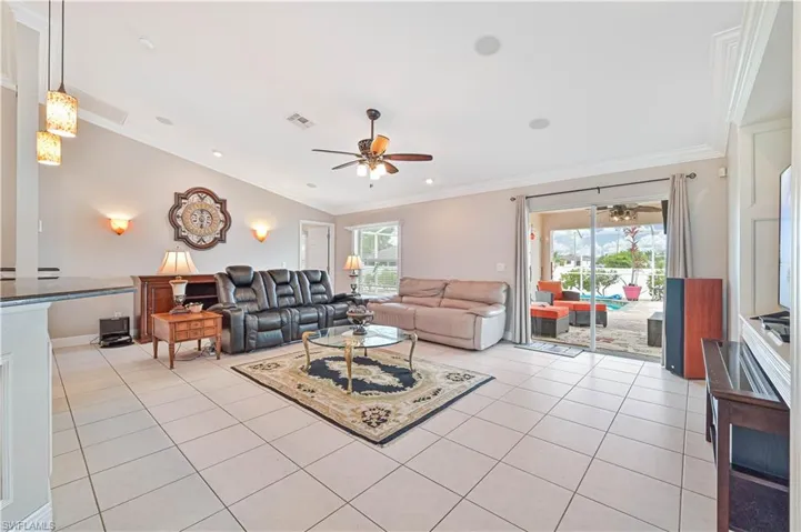 Living room featuring ceiling fan, crown molding, and light tile patterned flooring