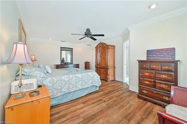 Bedroom with ceiling fan, dark hardwood / wood-style floors, and crown molding