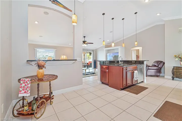 Kitchen with ceiling fan, hanging light fixtures, vaulted ceiling, sink, and light tile patterned flooring