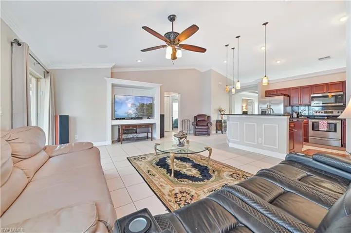 Tiled living room featuring ceiling fan, crown molding, and lofted ceiling